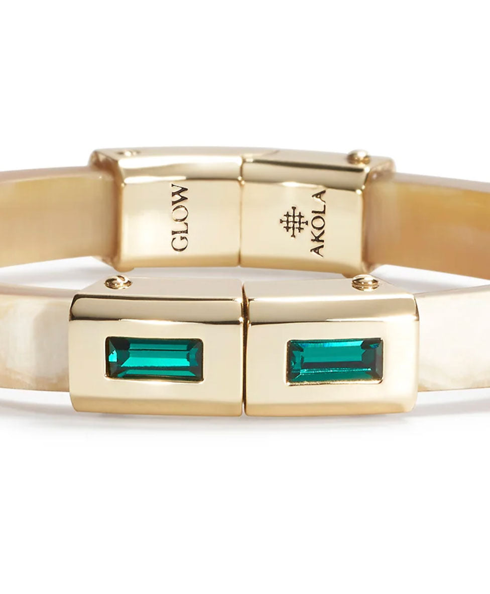 Gold bracelet with green gemstones and 'Akola' branding on a white background