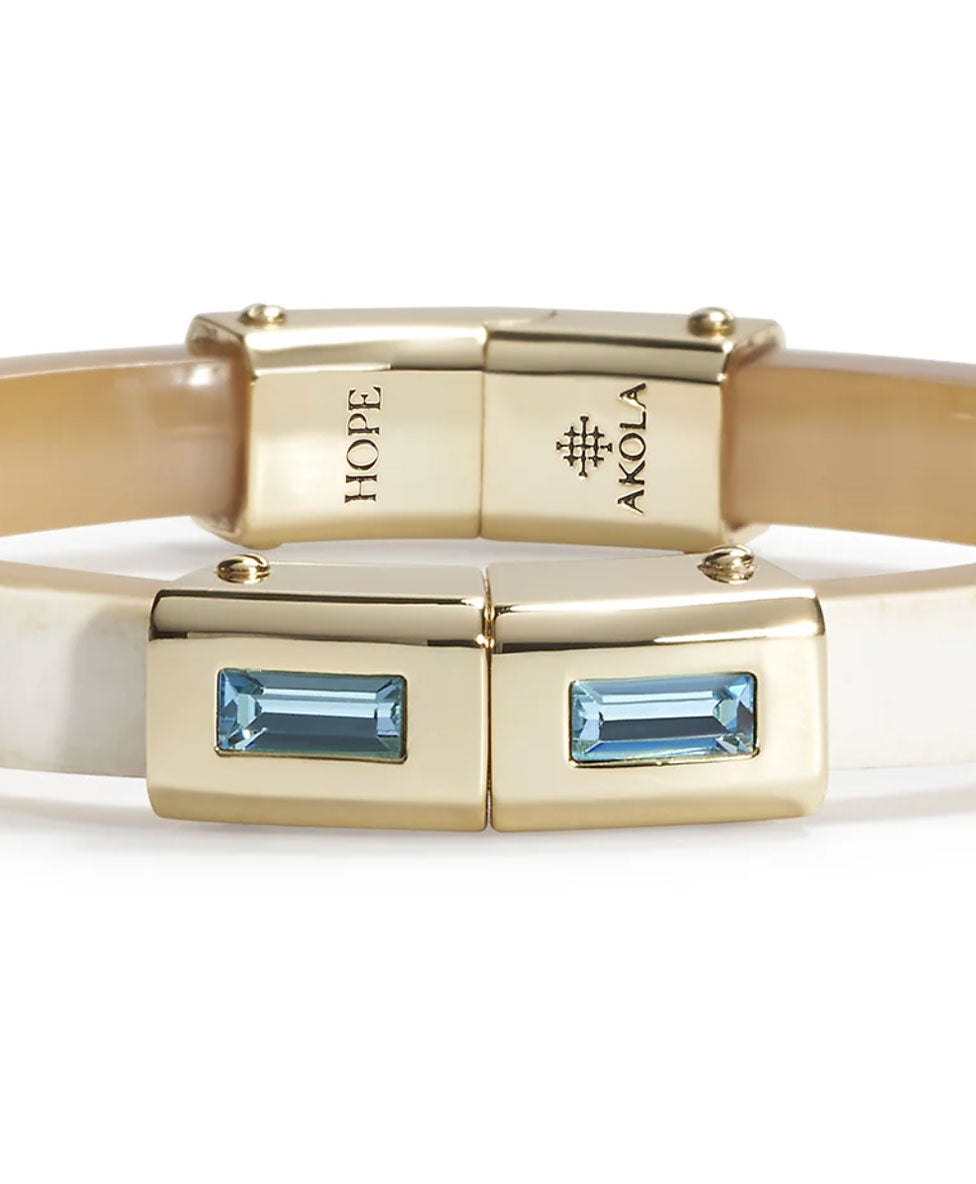 Gold bracelet with blue gemstones and 'Akola' Hope branding on a white background