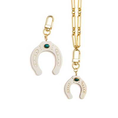 Gold chain with white horse shoe charm on a white background