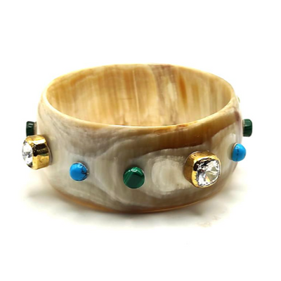 A bangle bracelet with hand carved Ankole horn featuring hand set gemstones and designer crystals, with gold, blue, and green accents.