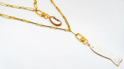 Akola cowrie charm layered with fish charm on a puka strand