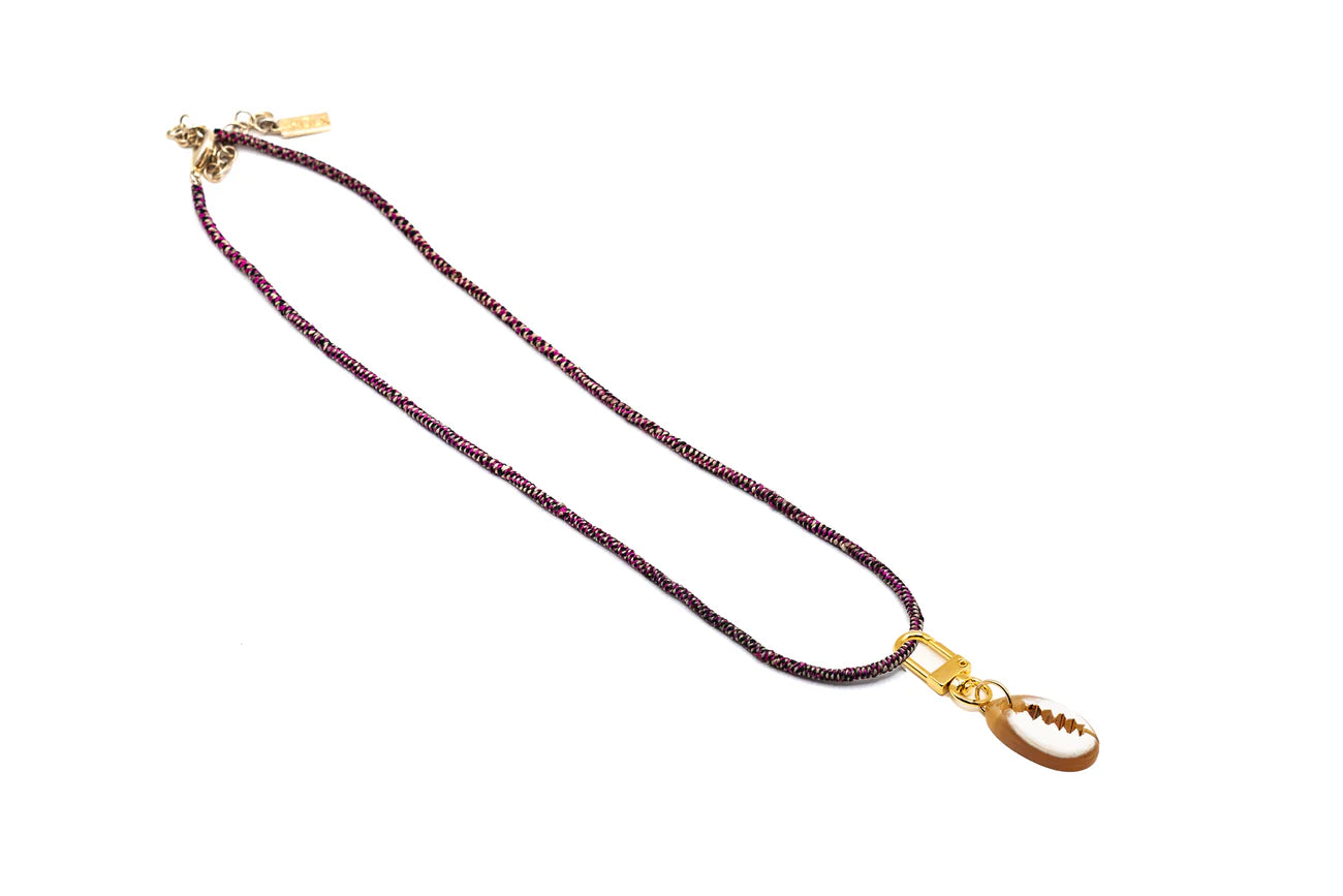 Akola cowrie horn charm on a braided raffia cord