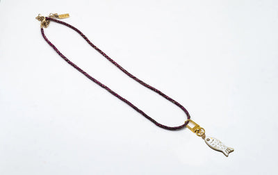 Petite horn fish charm hanging from a braided raffia bag handle